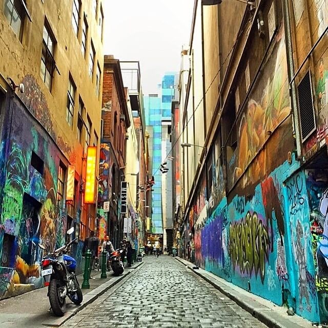 cobblestone street with walls of graffiti . 