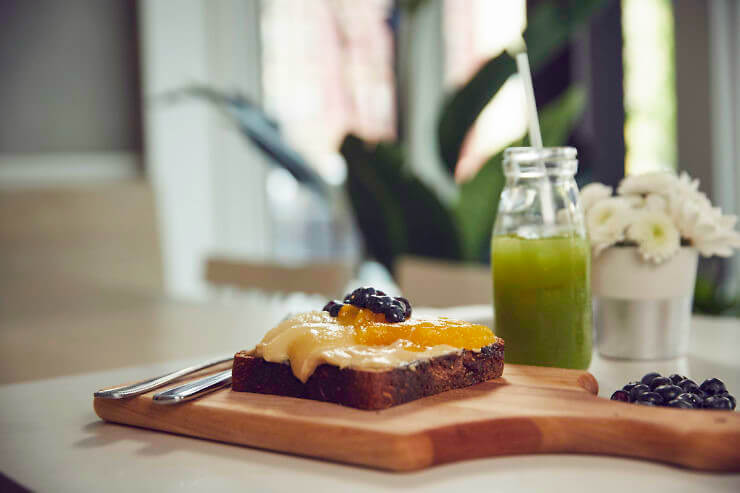 cashew butter toast with fruit and a bluestone lane juice in the background. 