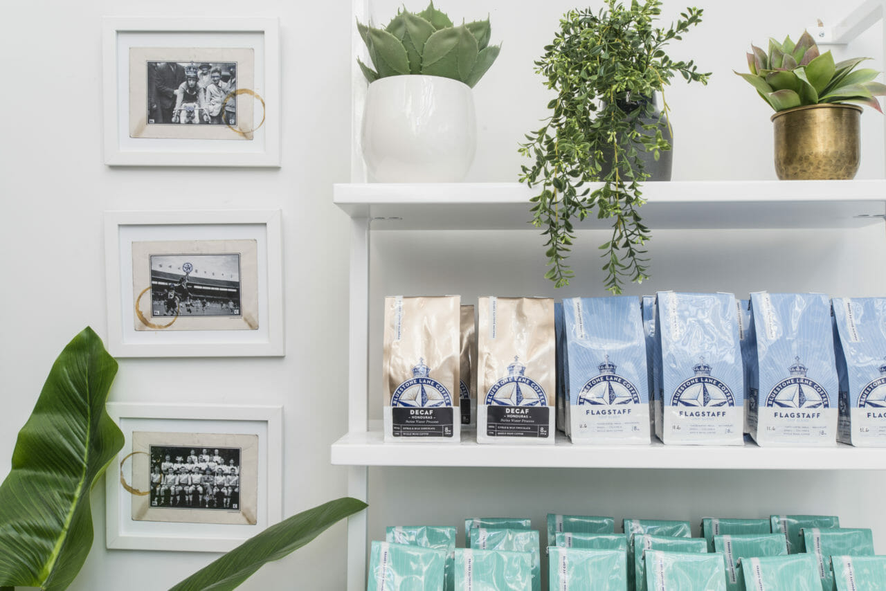 retail coffee bags on shelf with hanging plants.