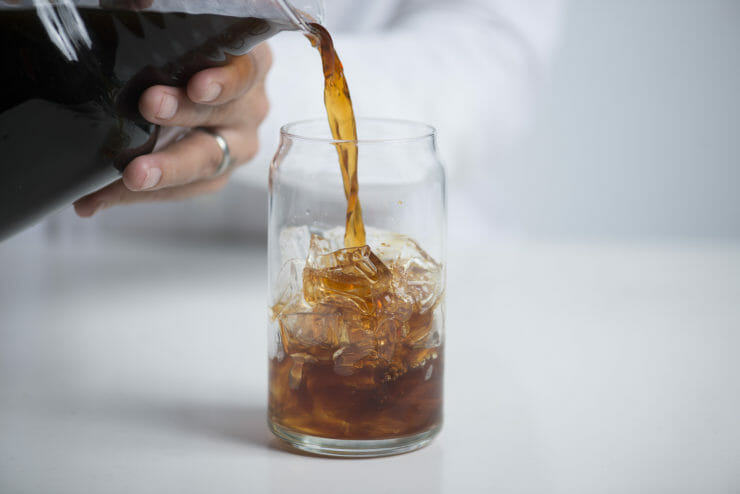 cold brew being poured into glass with ice. 