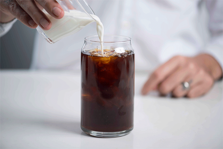 milk being added to glass with cold brew. 