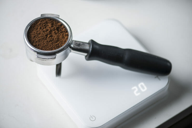 group handle on a scale with ground espresso in the group head basket. 
