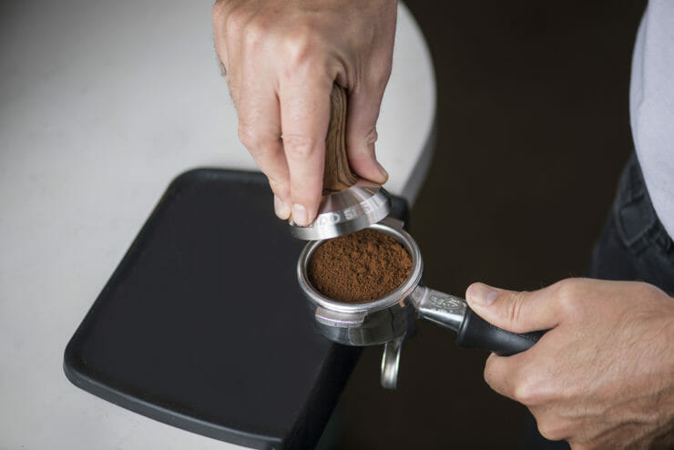hands tamping the ground espresso. 