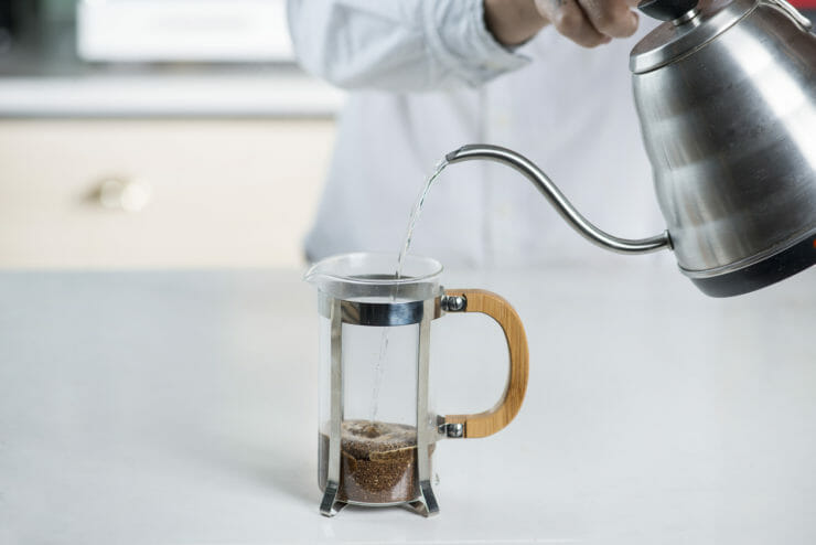 tea pot pouring boiling water into french press. 