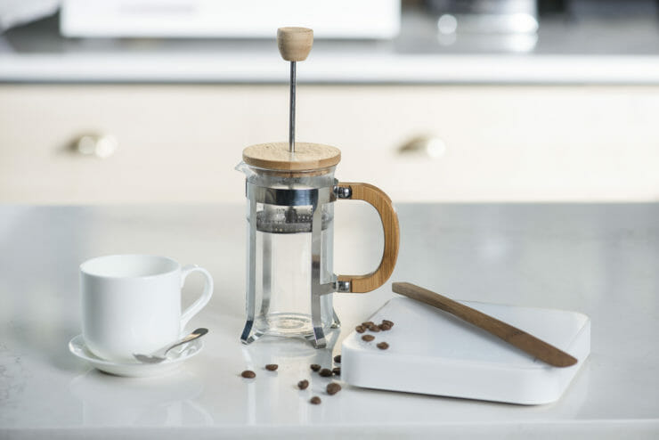 French Press on table with scale and coffee cup.