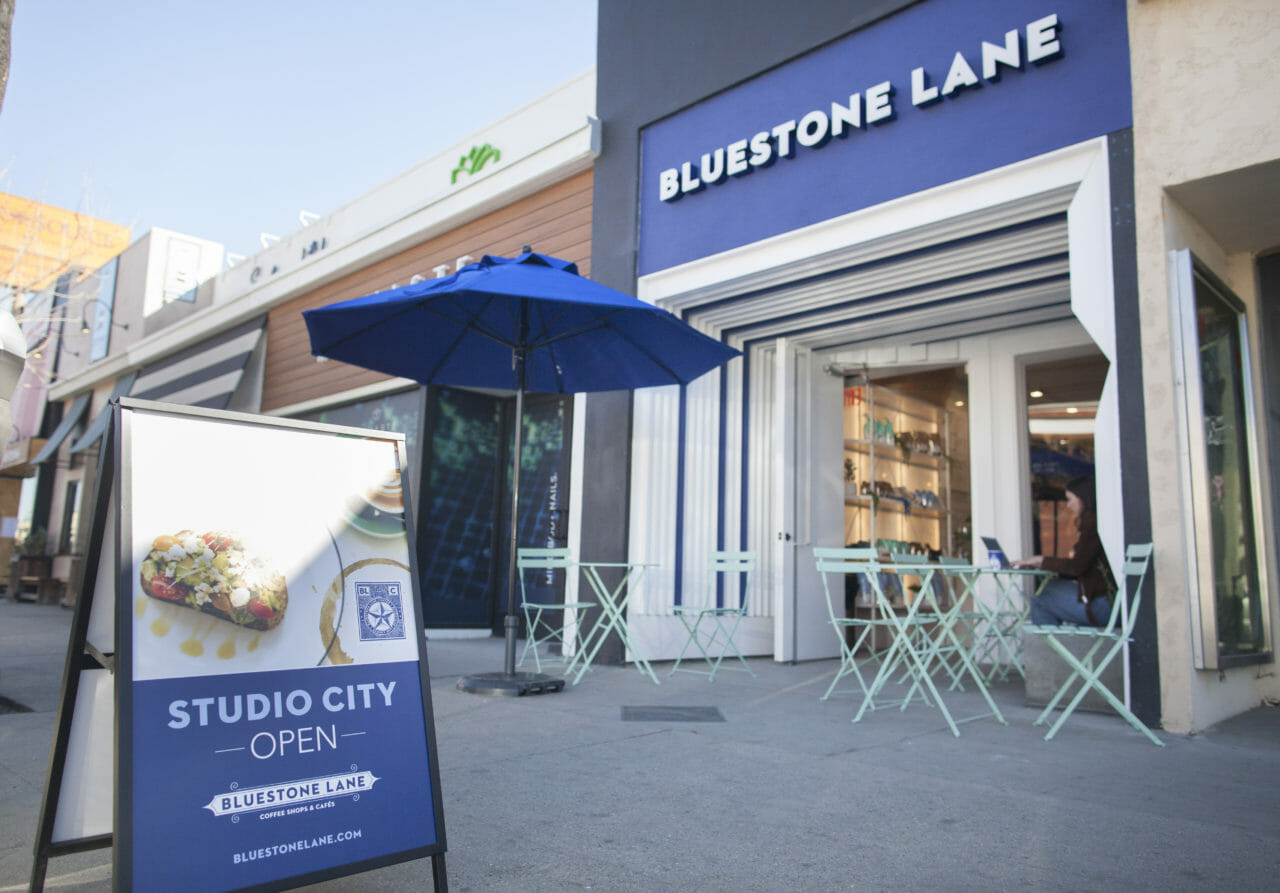 exterior of Studio City with a large blue umbrella and A frame.