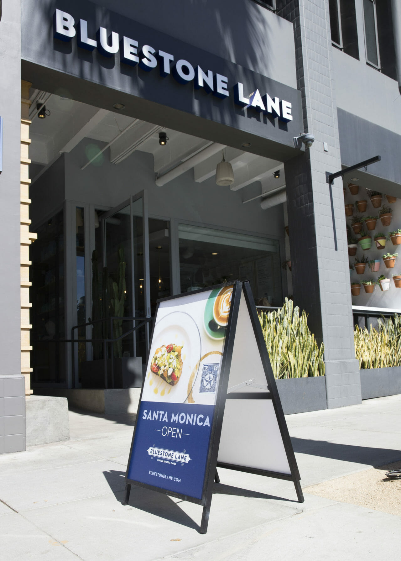 exterior image of Bluestone Lane Santa Monica with an A frame out the front.