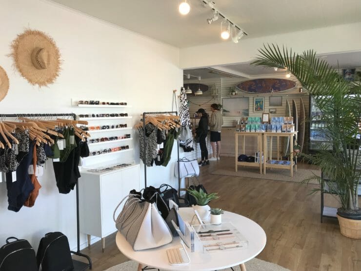 Interior of the Beach Collective with hanging swimwear, bags and a sunglasses wall. 