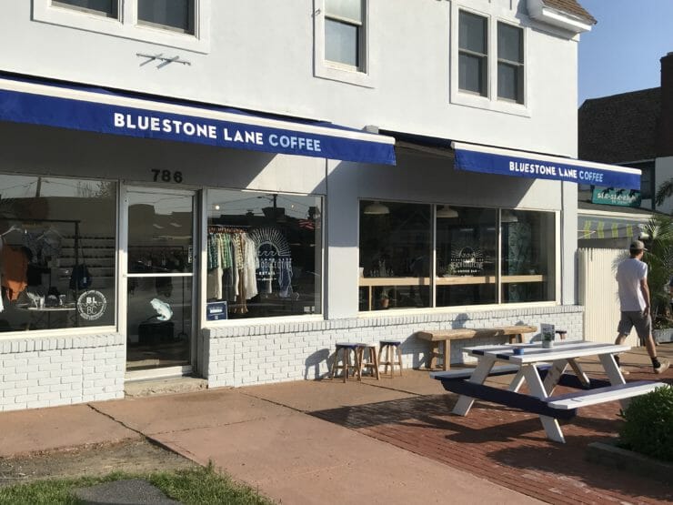 Store front of the Beach Collective with blue awnings and outside table. 