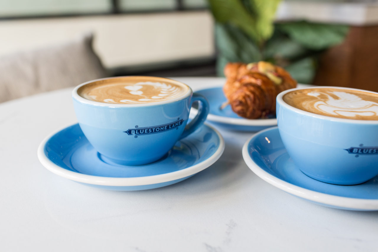 two hot coffees and a croissant on blue plates