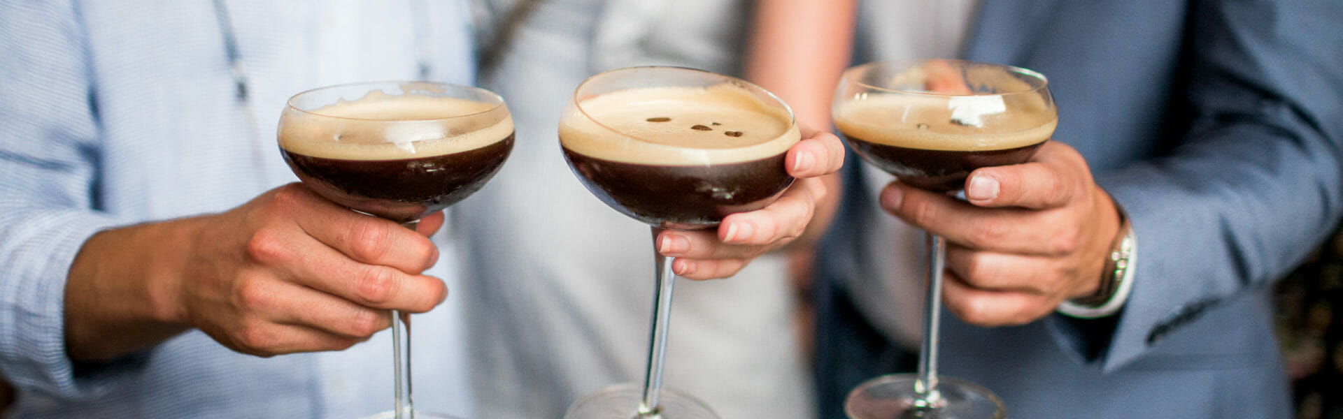 Three people holding espresso martinis