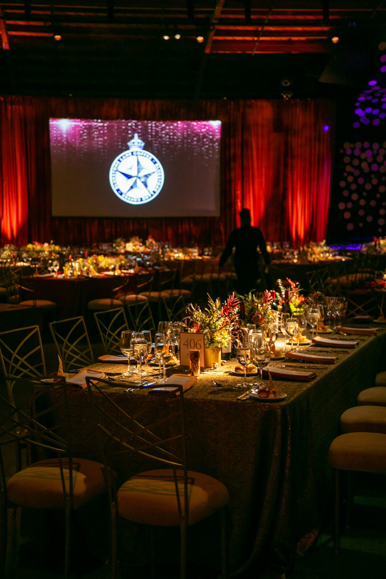 Gala set up with tables set and Bluestone Lane logo on the projector screen