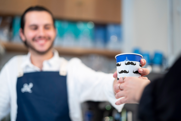 Barista handing coffee cup to a customer