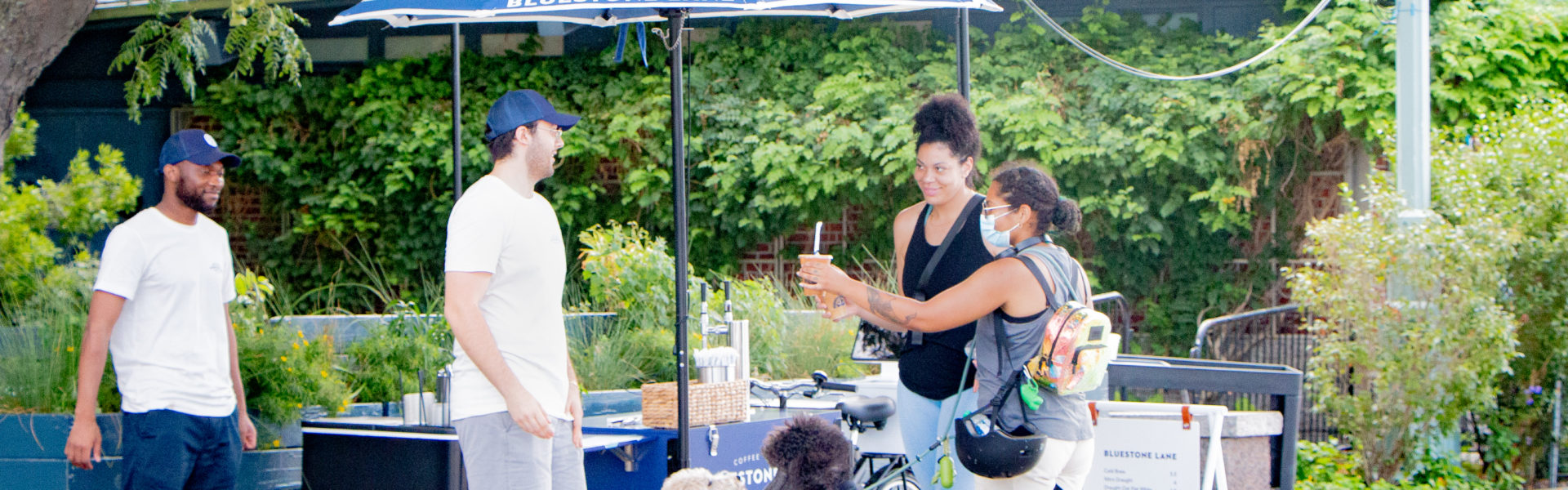 A Bluestone Lane coffee cart with three customers ordering