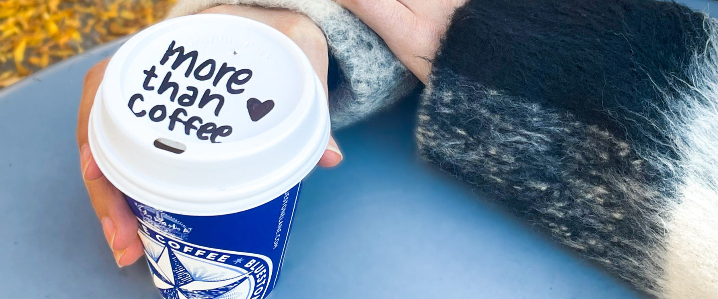 A Bluestone Lane coffee cup, with More than coffee written on the lid