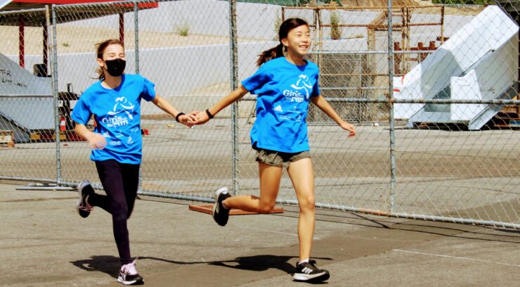 Two girls holding hands while runnning