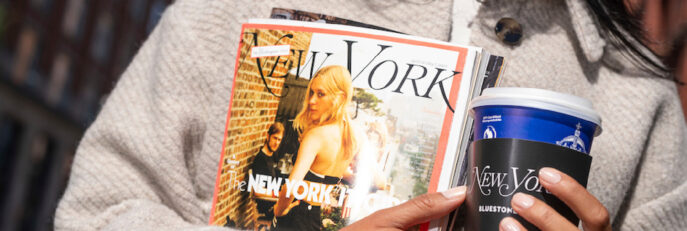A model holds a New York Mag in one hand and a Bluestone Lane takeaway cup in the other
